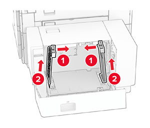The paper guides are tilted inward, and then removed from the tray.
